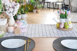 Easter decoration of colorful eggs in a basket and a rabbit on the kitchen table in a rustic style. Festive interior of a country house photo