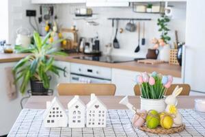 Key to house of cozy home with Easter decor with rabbit and eggs on table of kitchen. Building, design, project, moving to new house, mortgage, insurance, rent and purchase real estate photo