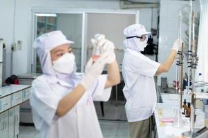 asiático hembra especialista en calidad controlar laboratorio examinando tomate ingrediente comida en investigación laboratorio, comida industria foto