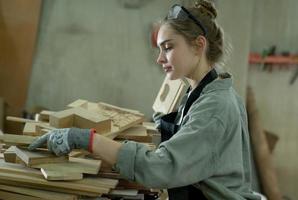 joven hembra carpintero trabajando proyecto en su taller. hembra carpintero haciendo de madera mueble. foto