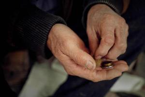 el manos de un mayor hombre considerar pequeño cosas. concepto de pobreza y bajo pensiones foto