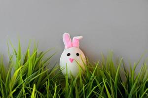 Easter holiday, a handmade egg made by a child in the form of a rabbit on a grey background. photo