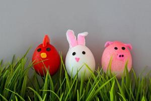 Easter holiday, a handmade egg made by a child in the form of a rabbit , chicken  and pig against a grey background. photo