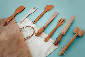 Wooden kitchen utensils hammer, rolling pin, fork, spatula and eco paper bag photo