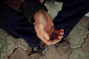 Close up extended arm of an elderly man asking for help or money. Poverty, donations, unemployment. photo