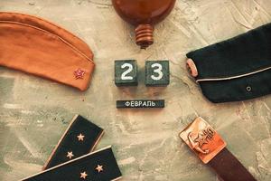 Flask, cap, soldier's military belt,shoulder straps  of the war years and a wooden calendar with the date February 23. Fatherland defender day. photo