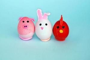 Easter holiday, a handmade egg made by a child in the form of a rabbit , chicken  and pig against a blue background. photo