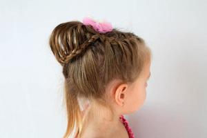 Assembled up hairdo of a little girl from pigtails on a white background. Home hairstyle, hands mom. photo