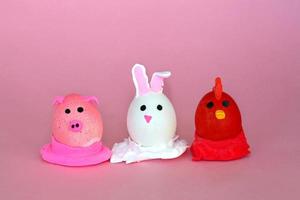 Easter holiday, a handmade egg made by a child in the form of a rabbit , chicken  and pig against a pink background. photo