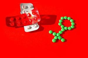 Gender symbol made from green pills or tablets  on a red background. photo