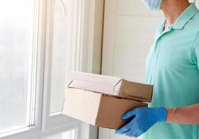 Delivery man holding cardboard boxes in medical rubber gloves and mask. Copy space. photo
