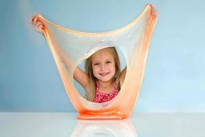 Funny girl holdin a slime in front of her face and looking through its hole. photo