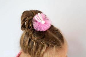 Assembled up hairdo of a little girl from pigtails on a white background. Home hairstyle, hands mom. photo