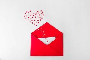 Opened red envelope and many felt hearts on white background with place for text. Love letter mail correspondence relationship. Valentines day concept. Top view. photo