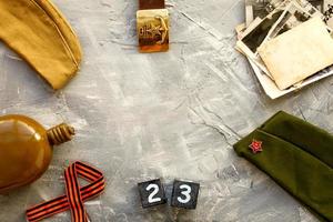 Flask, cap, soldier belt with a five-pointed star with a hammer and sickle and old photographs a wooden calendar  February 23 . Fatherland defender day. photo