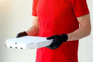 un hombre manos caucho guantes con un caja Pizza . comida entrega durante el cuarentena de el coronavirus pandemia. foto