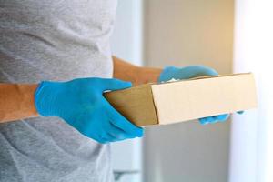 Closeup male hands in blue rubber gloves hold cardboard boxes. photo