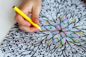 Close-up of girls hands draw with crayons in antistress coloring. photo