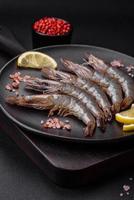 Tiger prawn or langoustine raw with spices and salt on a wooden cutting board photo