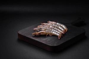 Tigre gamba o langostinos crudo con especias y sal en un de madera corte tablero foto
