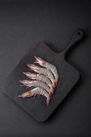 Tiger prawn or langoustine raw with spices and salt on a wooden cutting board photo