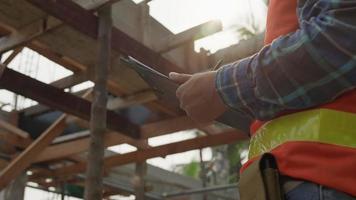 el inspector o ingeniero está inspeccionando la construcción y el aseguramiento de la calidad de la nueva casa usando una lista de verificación. ingenieros o arquitectos o contratistas trabajan para construir la casa antes de entregársela al propietario video