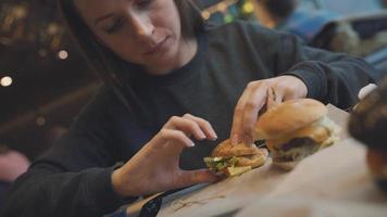 mujer come un hamburguesa en un café video