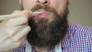 Bearded man eating sushi with a chopsticks video