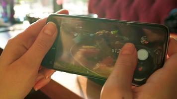 flicka gör en Foto av kaffe på en smartphone i en Kafé stänga upp video