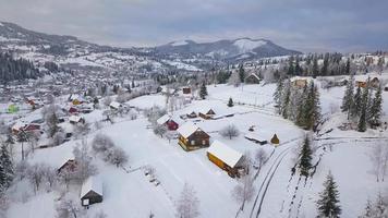 Flight over snowy mountain village and coniferous forest. Clear sunny frosty weather video