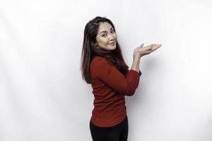 Excited Asian woman dressed in red, pointing at the copy space beside her, isolated by white background photo