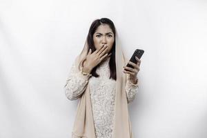 A depresses Asian Muslim woman wearing a headscarf looks stressed while talking on the phone isolated by white background photo