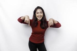 Excited Asian woman dressed in red, pointing down at the copy space, isolated by white background photo