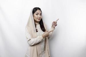 Young Asian Muslim woman smiling while pointing to copy space beside her photo