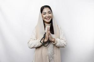 Portrait of a young beautiful Asian Muslim woman wearing a headscarf gesturing Eid Mubarak greeting photo