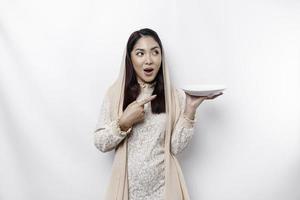 An Asian Muslim woman is fasting and hungry and holding utensils cutlery while looking aside thinking about what to eat photo