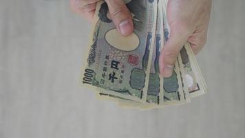 japonés yen dinero. cerca arriba de el japonés yen en mano. moneda de Japón ese es usado a cambiar, comprar, vender, acumular, invertir, financiero, intercambiar tasa, valor, contabilidad, internacional intercambiar video