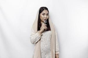 An Asian Muslim woman is fasting and hungry and holding utensils cutlery while looking aside thinking about what to eat photo