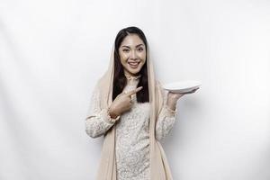 An Asian Muslim woman is fasting and hungry and holding utensils cutlery while looking aside thinking about what to eat photo