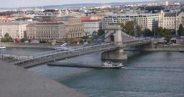 Ship sails under a chain bridge in Budapest next to parliament video