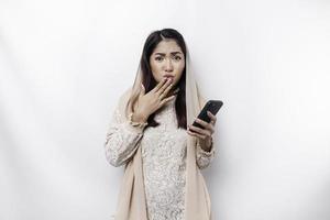 A depresses Asian Muslim woman wearing a headscarf looks stressed while talking on the phone isolated by white background photo