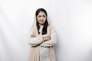 A thoughtful young Asian Muslim woman wearing headscarf while looking aside, isolated by a white background photo