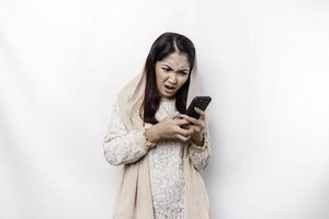 A depresses Asian Muslim woman wearing a headscarf looks stressed while talking on the phone isolated by white background photo