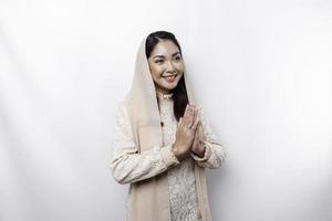 Portrait of a young beautiful Asian Muslim woman wearing a headscarf gesturing Eid Mubarak greeting photo