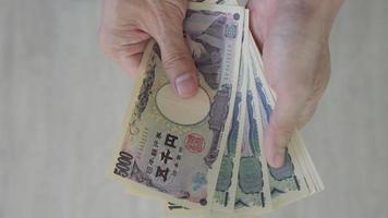 japonês iene dinheiro. fechar acima do a japonês iene em mão. moeda do Japão este é usava para mudar, comprar, vender, acumular, investir, financeiro, troca avaliar, valor, contabilidade, internacional troca video