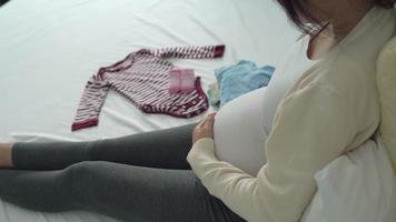 mor är hopfällbar bebis kläder till förbereda för de kommande bebis. en gravid kvinna är kontroll nödvändig för nyfödd. begrepp förbereda av graviditet beredskap för mödrar. video