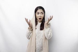 Shocked Asian Muslim woman wearing headscarf with her mouth wide open, isolated by white background photo