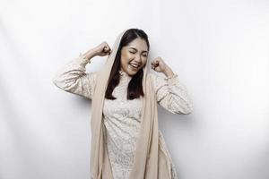 A young Asian Muslim woman with a happy successful expression wearing a hijab isolated by white background photo