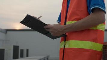 Asian maintenance engineer works on the roof of factory. contractor inspect compressor system and plans installation of air condition systems in construction. Checklist, inspector, control video