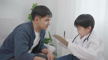 feliz padre soltero jugando a aprender ocupacional para un niño pequeño. la familia divertida está feliz y emocionada en la casa. padre e hijo divirtiéndose pasando tiempo juntos. vacaciones, médico, desarrollo. video